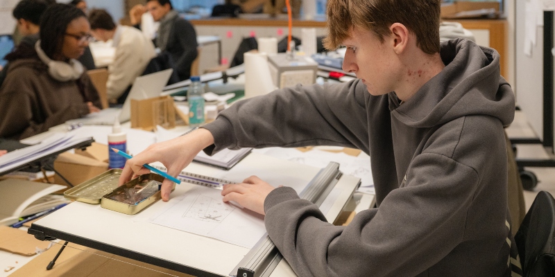 A student using a drafting table in the design studio, Campus East